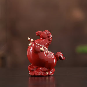 Red ceramic rooster figurine with gold accents on a dark surface
